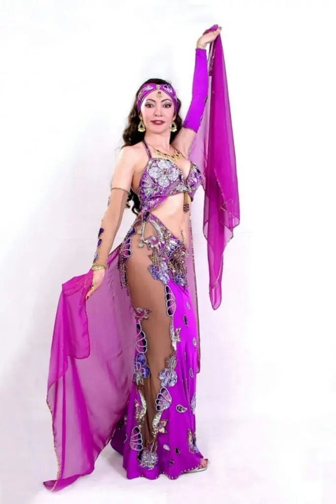 Belly dancer in a purple costume holding a long silk veil