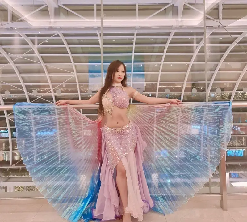 Belly dancer with iridescent wings at an indoor venue
