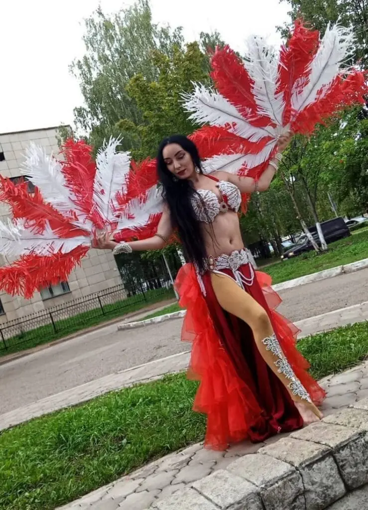 Belly dancer with red and white feather fans outdoors