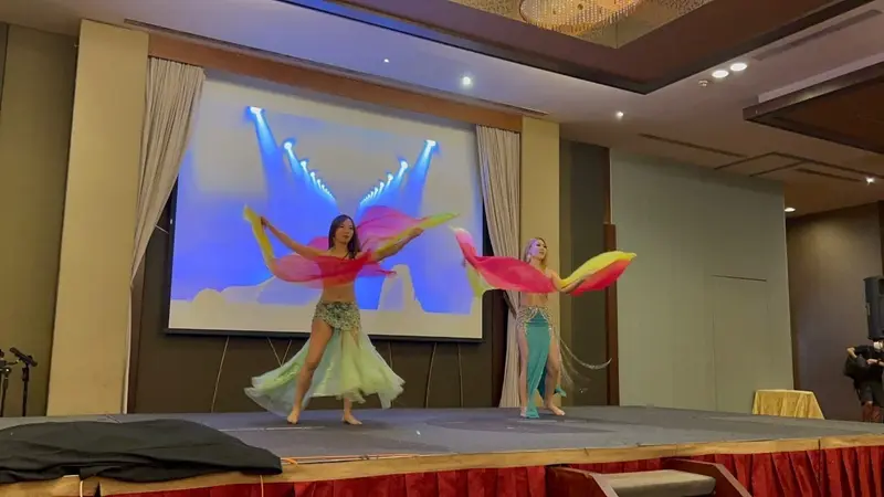 Two belly dancers performing with silk fans on a hotel stage